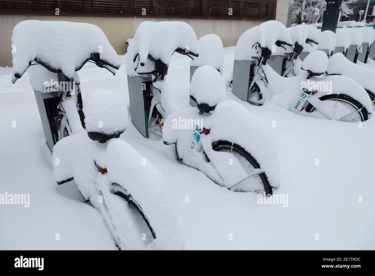 Madrid, Spagna - 09 gennaio 2021: Fila di biciclette elettriche del servizio pubblico della società EMT, Bicimad, sepolto nella neve, in una giornata innevata, a causa di t Foto Stock