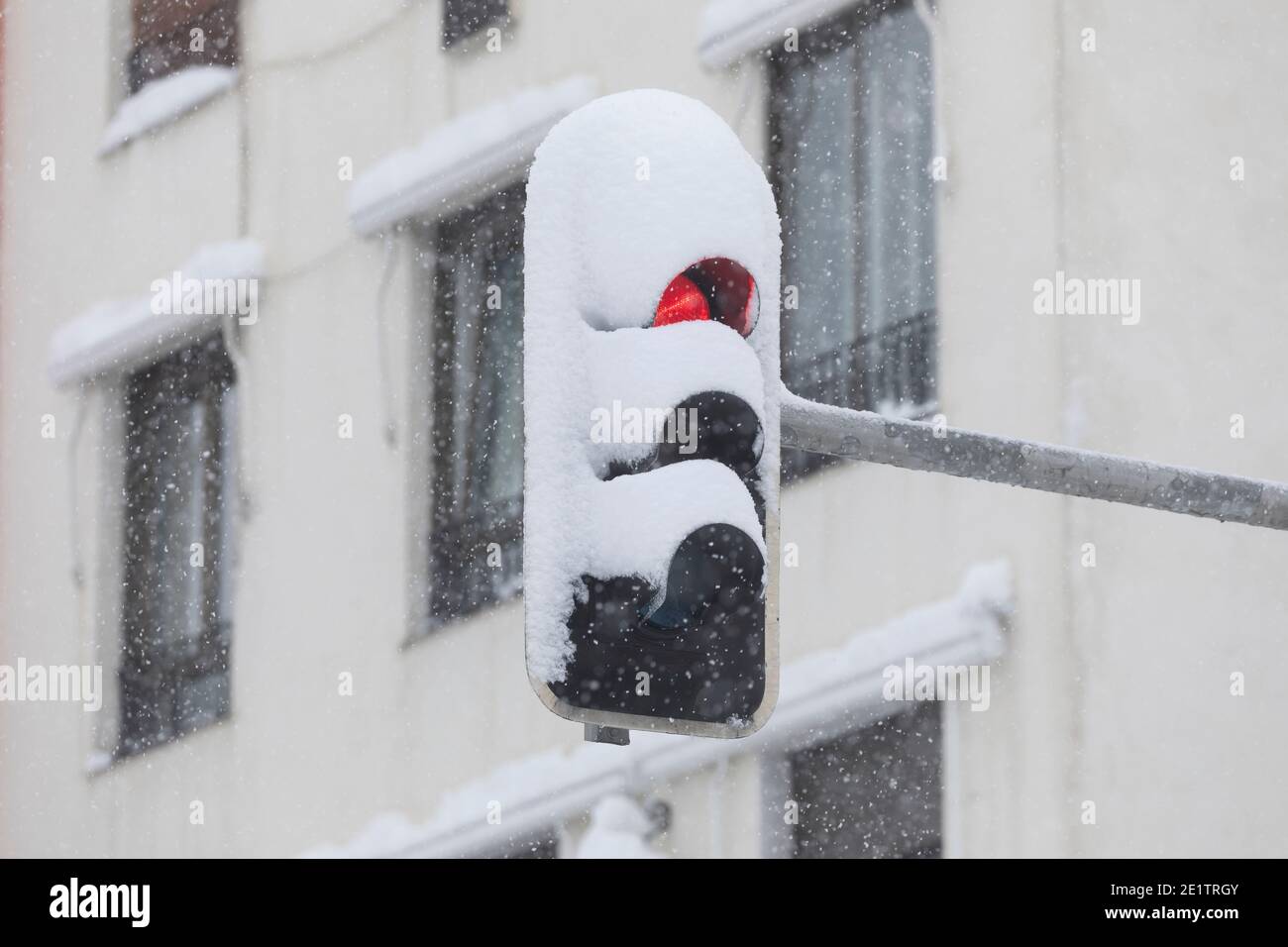 Madrid, Spagna - 09 gennaio 2021: Un semaforo rosso, completamente coperto di neve, in una giornata innevata, a causa del fronte polare freddo Filomena. Foto Stock