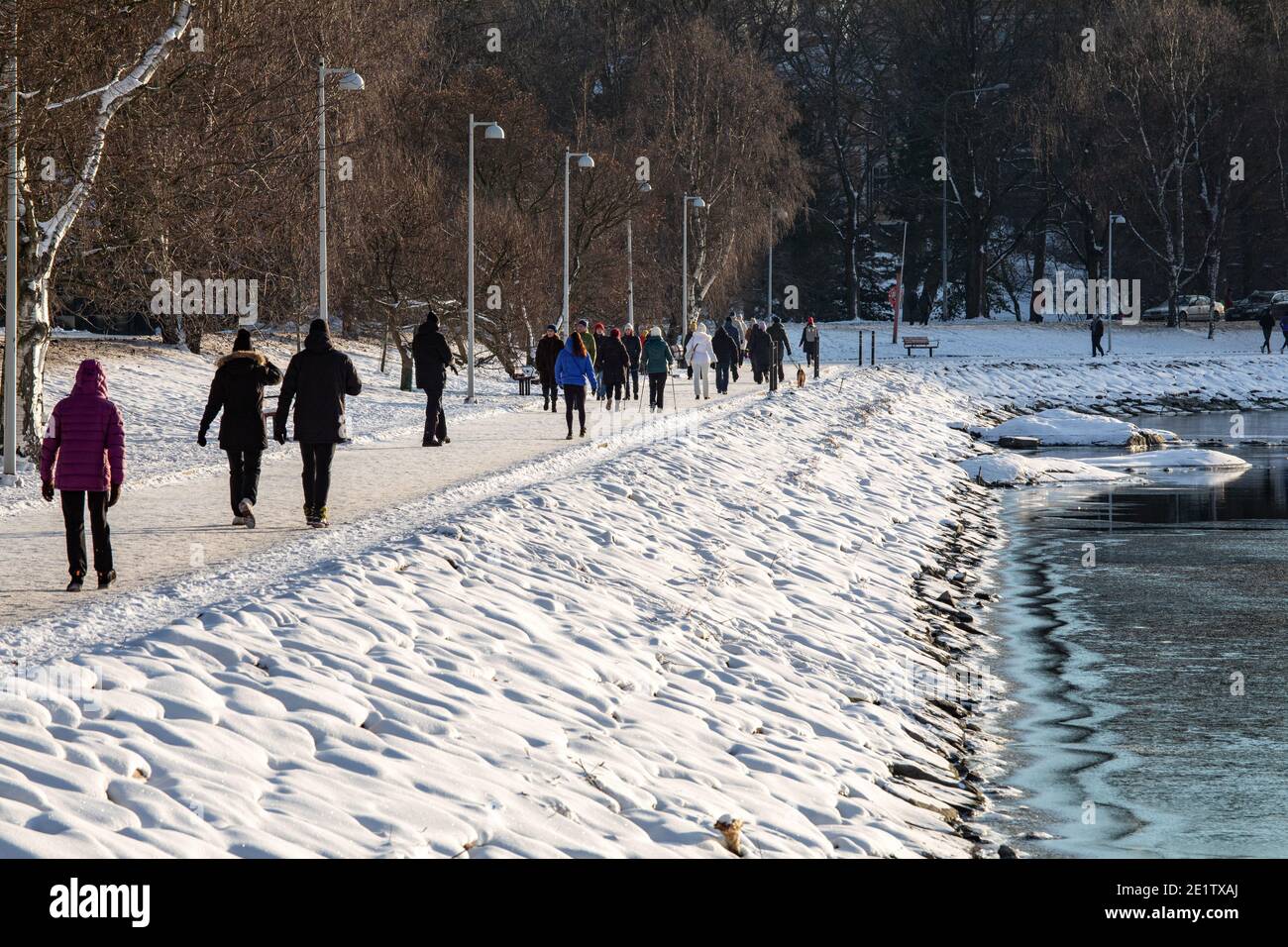 Persone che hanno una passeggiata in una giornata invernale presso la baia di Humallahti nel quartiere Taka-Töölö di Helsinki, Finlandia Foto Stock