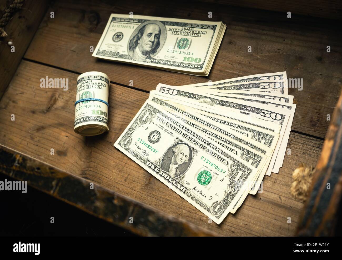Quantità di banconote statunitensi su pile di denaro e in rotolo in cassetto di legno. Contanti di cento fatture del dollaro, fondo di valuta di carta. Foto Stock