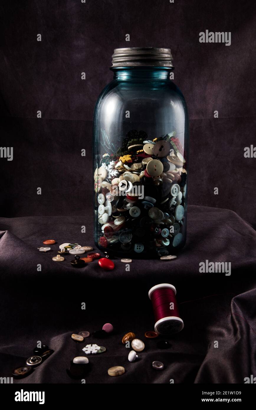 Biberon vintage o "vasetto di rason" pieno di vecchi bottoni. Il colore verdolino e opaco del vaso è un segno di spia delle vecchie bottiglie di vetro. Foto Stock