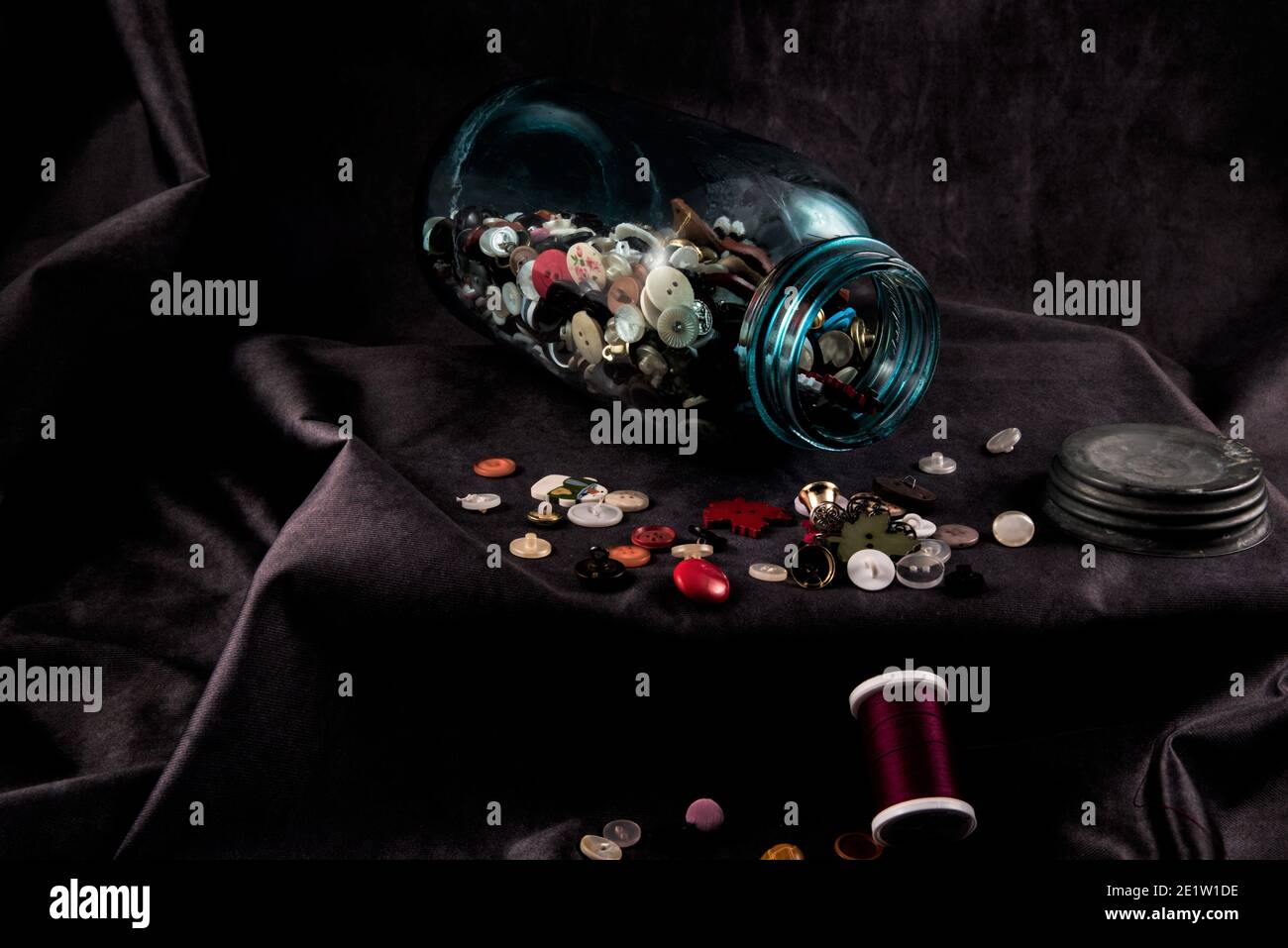 Biberon vintage o "vasetto di rason" pieno di vecchi bottoni. Il colore verdolino e opaco del vaso è un segno di spia delle vecchie bottiglie di vetro. Foto Stock