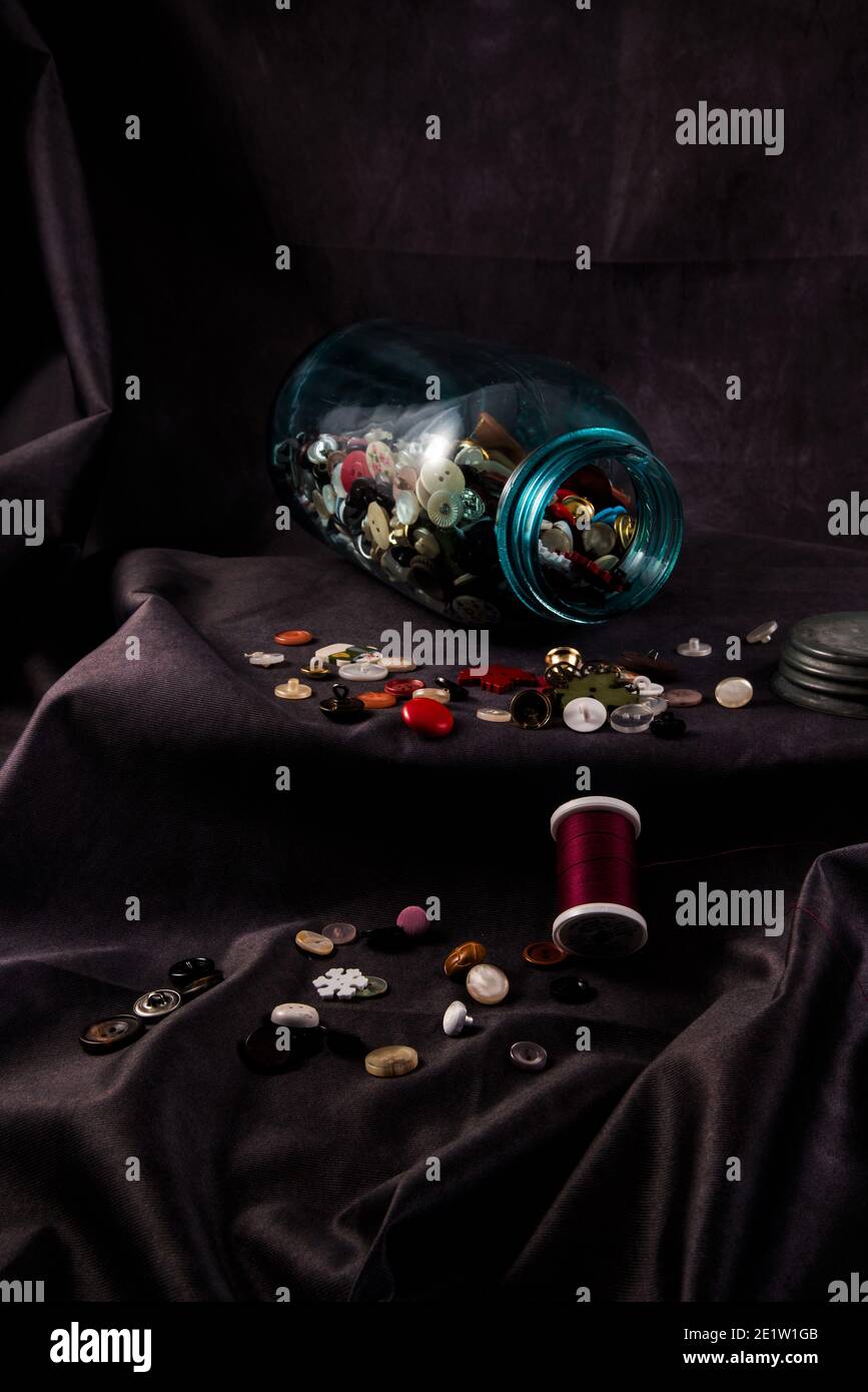 Biberon vintage o "vasetto di rason" pieno di vecchi bottoni. Il colore verdolino e opaco del vaso è un segno di spia delle vecchie bottiglie di vetro. Foto Stock