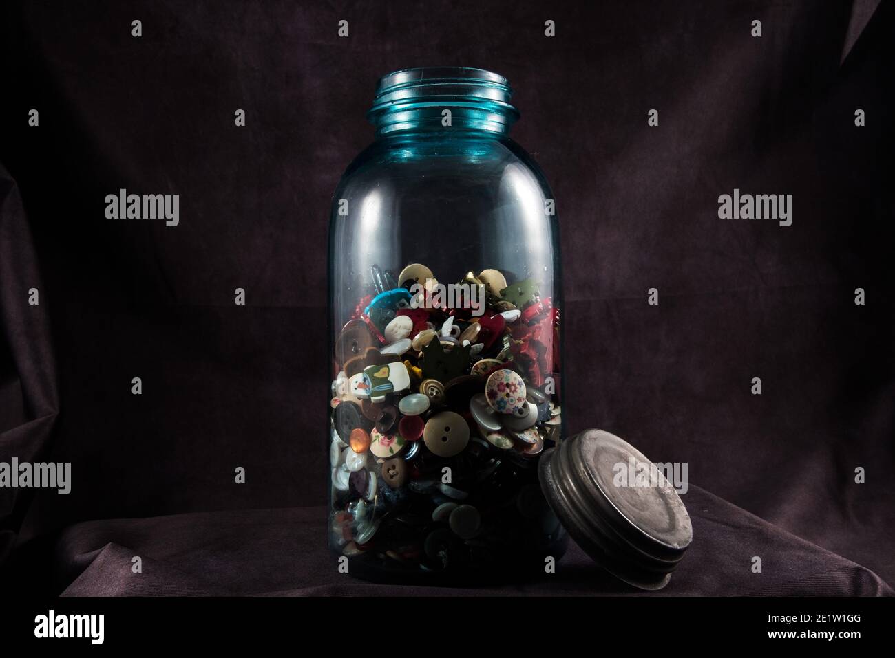 Biberon vintage o "vasetto di rason" pieno di vecchi bottoni. Il colore verdolino e opaco del vaso è un segno di spia delle vecchie bottiglie di vetro. Foto Stock