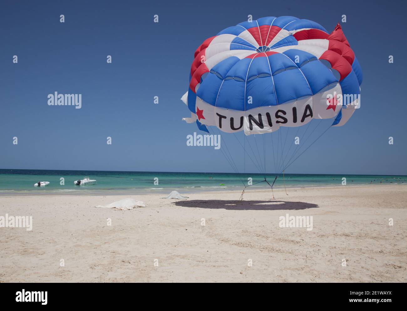 Splendido paesaggio di spiaggia a Djerba con un po' di brezza in movimento il parchute ancorato nella sabbia Foto Stock