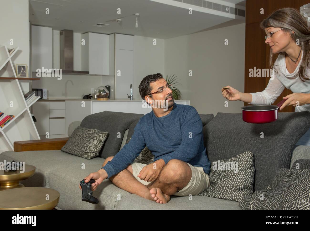 la donna sta cercando di nutrire un uomo che è occupato giocare a videogiochi nel tuo appartamento cittadino Foto Stock