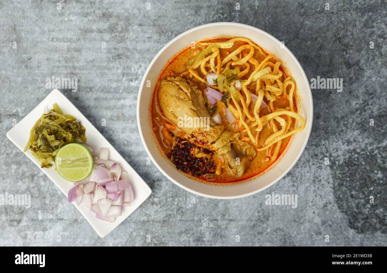 Cibo tailandese, zuppa di Noodle al curry in stile settentrionale con pollo su tavolo in cemento grigio. Foto Stock