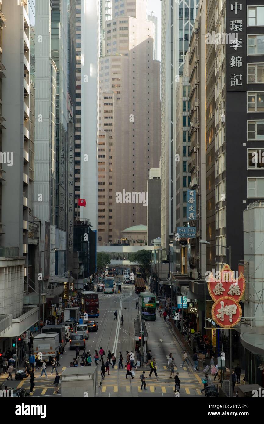 Des Voeux Road di Hong Kong si anima con la vibrante energia della vita urbana, incorniciata dall'iconico Standard Chartered Bank Building e dal vivace corvo Foto Stock