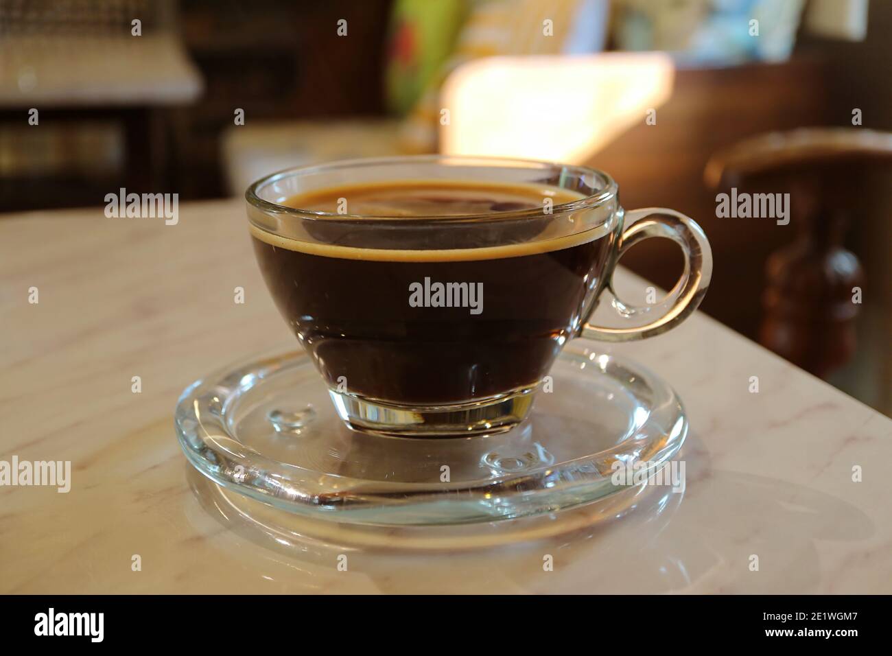 Caffè nero caldo in una tazza trasparente isolata sul tabella Foto Stock