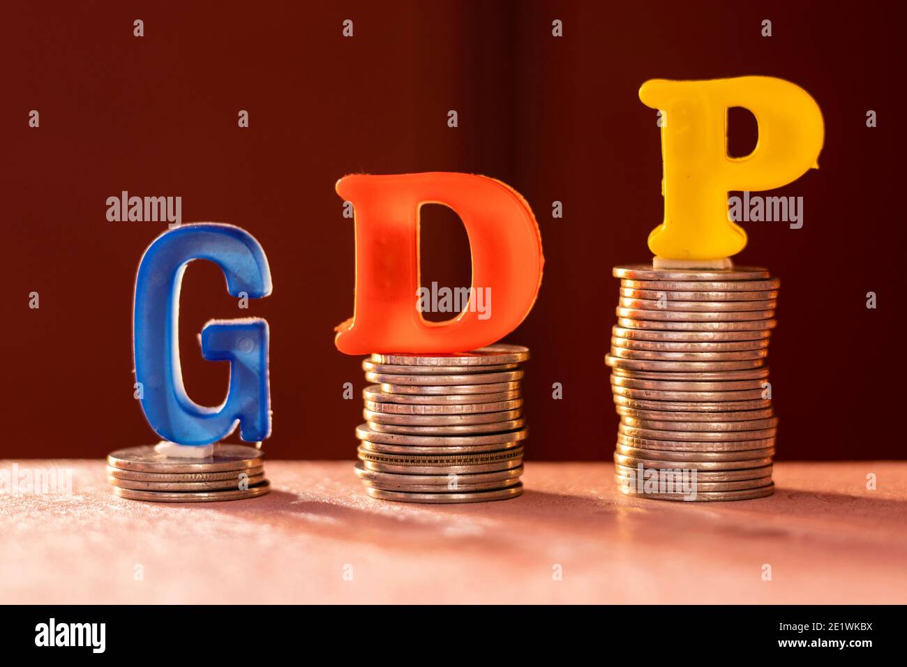 G D P alfabeti colorati su monete che mostrano una tendenza verso l'alto Foto Stock