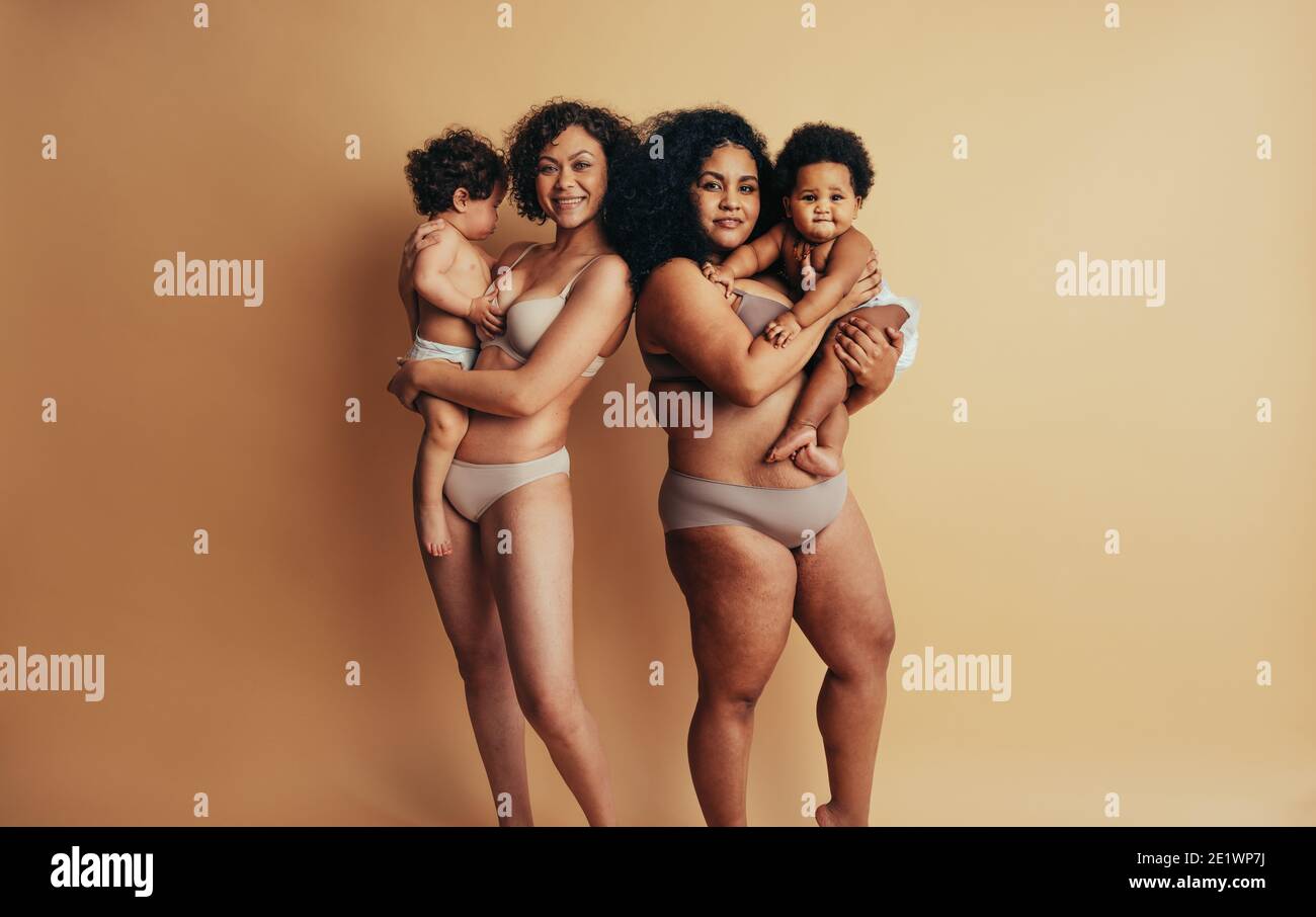 Madri e bambini che si levano in piedi insieme il giorno delle madri. Donne con corpi postpartum che tengono i loro bambini nelle loro braccia. Foto Stock