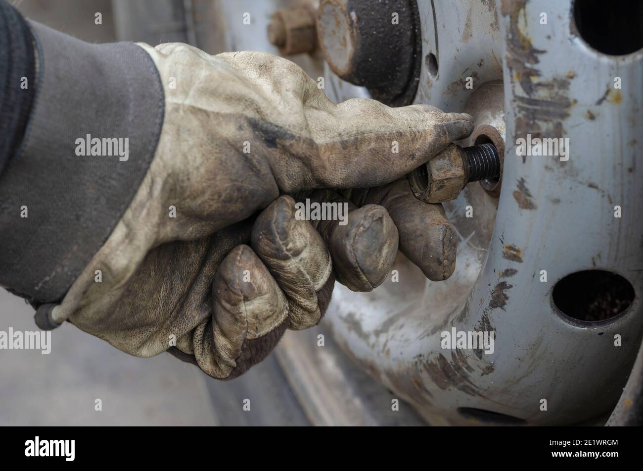 Servizio pneumatici, concetto di servizio auto. Avvitare manualmente il guanto sviti il bullone di fissaggio sulla ruota. Sostituzione di uno pneumatico sgonfio. Vista laterale. Messa a fuoco selettiva. Foto Stock