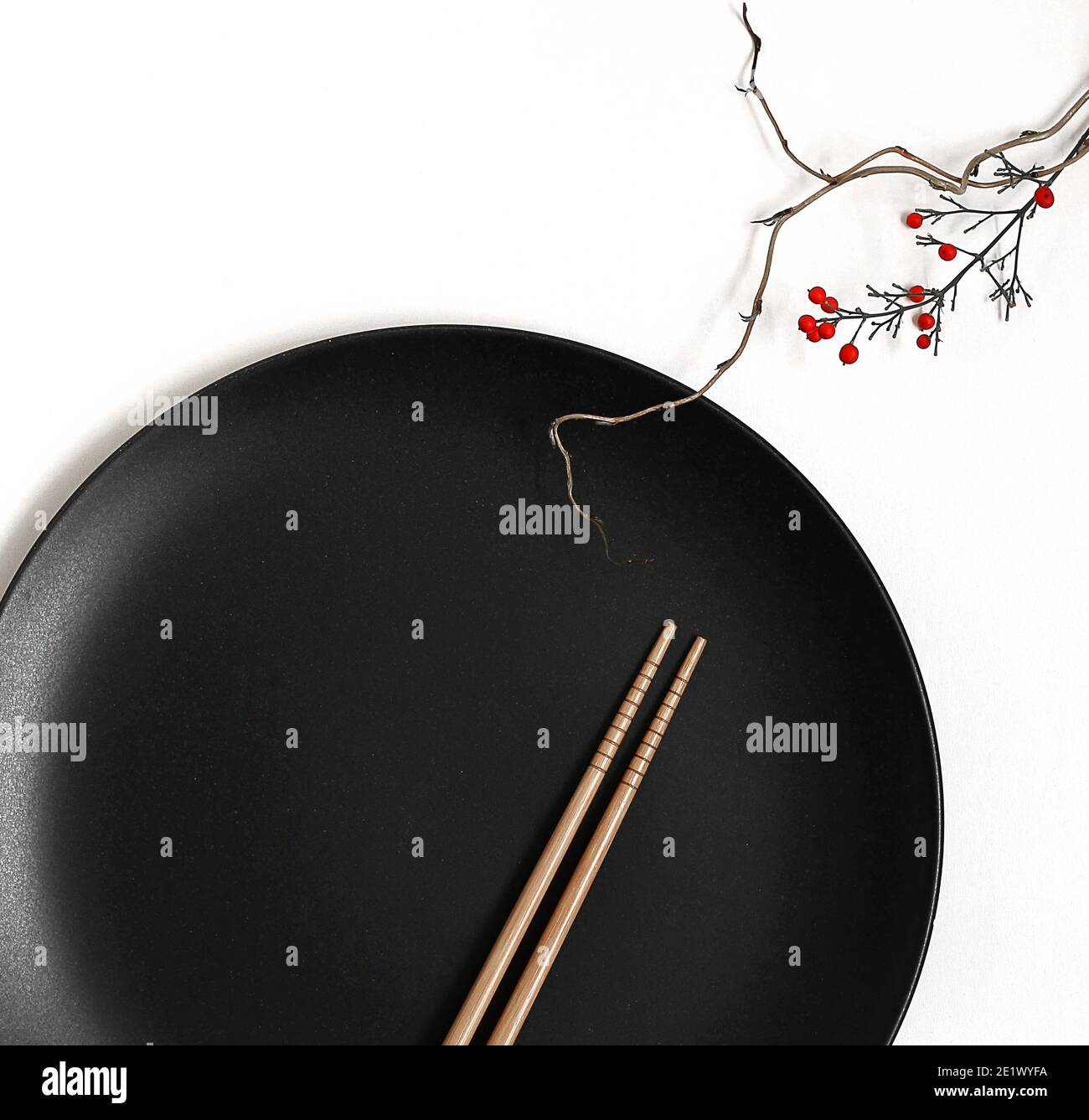 Piatto rotondo nero, due chopsticks e bambù giapponese in morbido fuoco su sfondo bianco. Ispirazione giapponese, disposizione dei tavoli Foto Stock