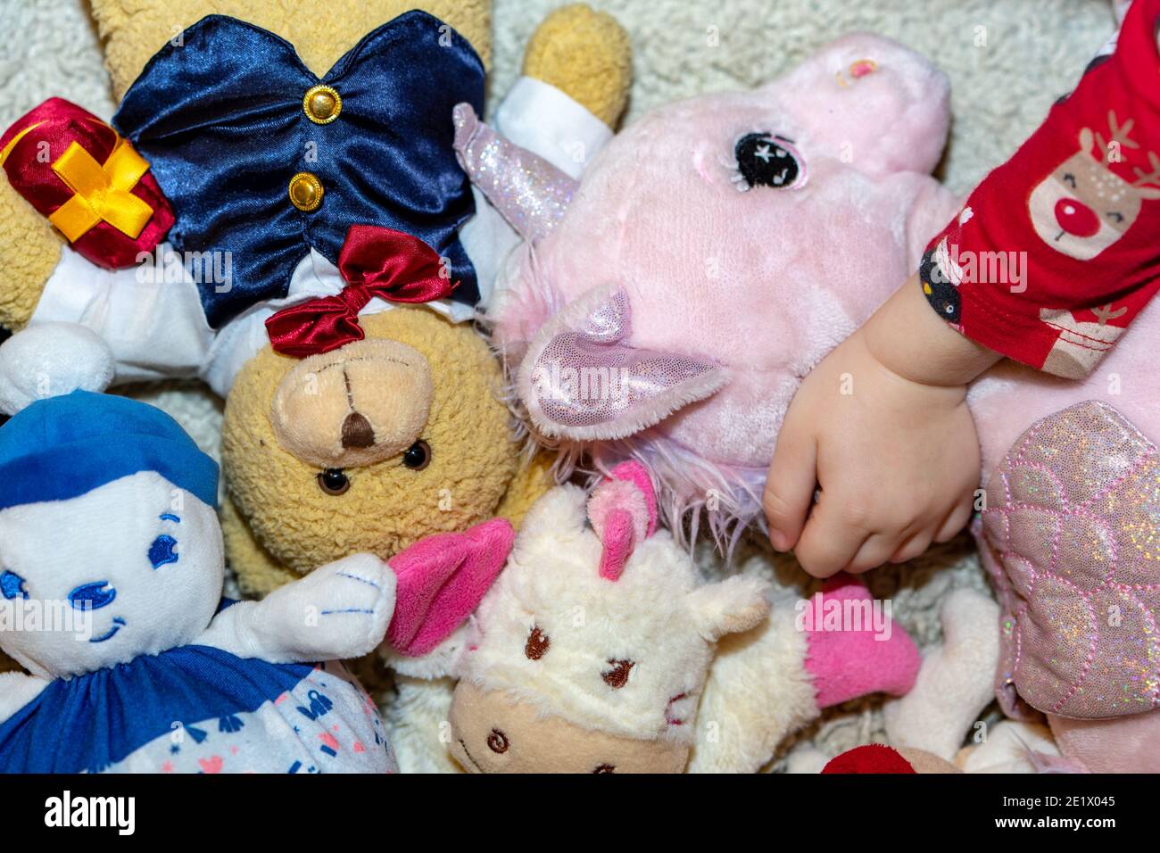 Bambina cosset il suo giocattolo unicorno preferito sul pavimento mentre gioca nella sua stanza Foto Stock