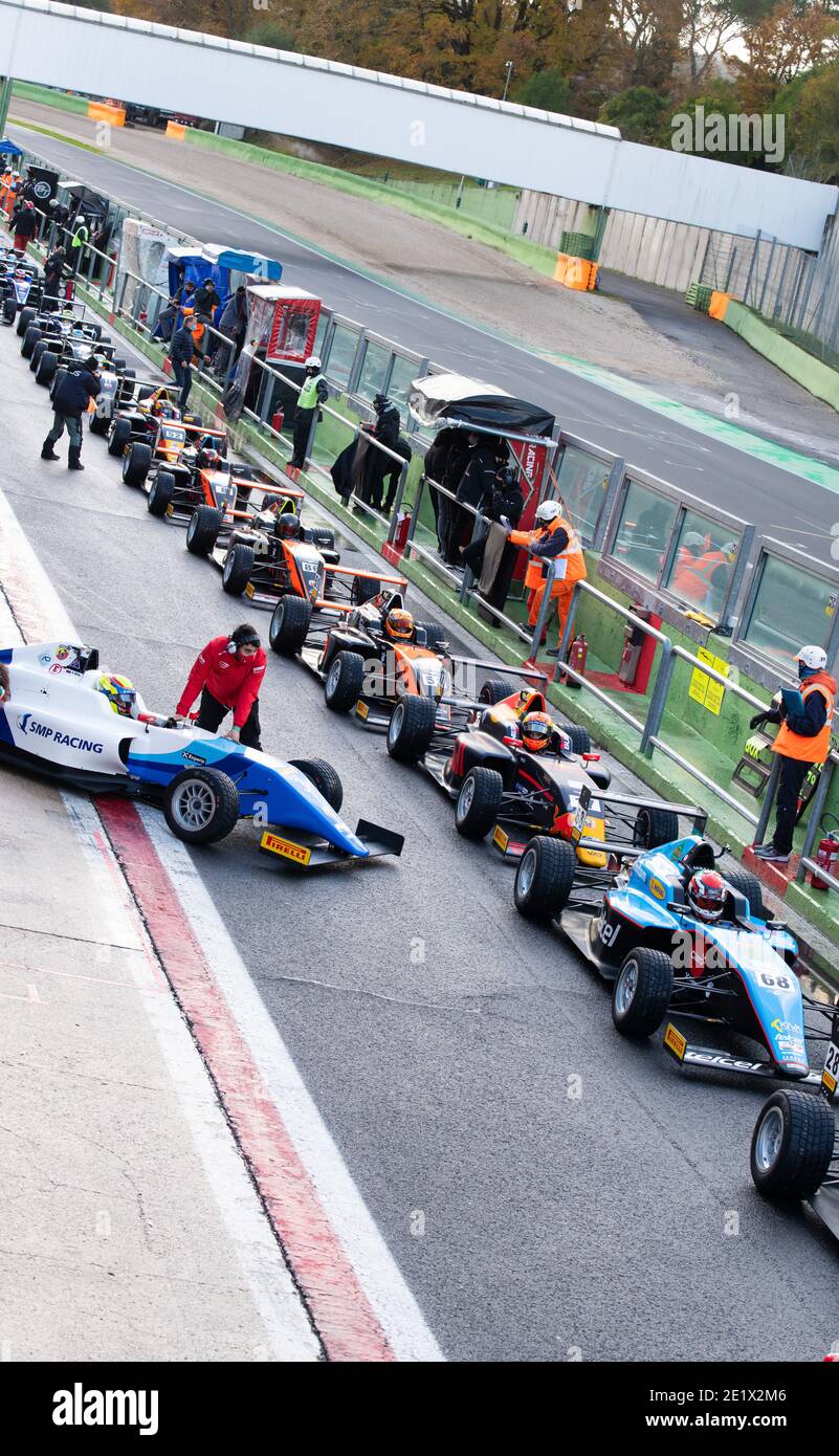Gran numero di auto da corsa in formula allineate su pista asfaltata nel circuito pit lane Foto Stock