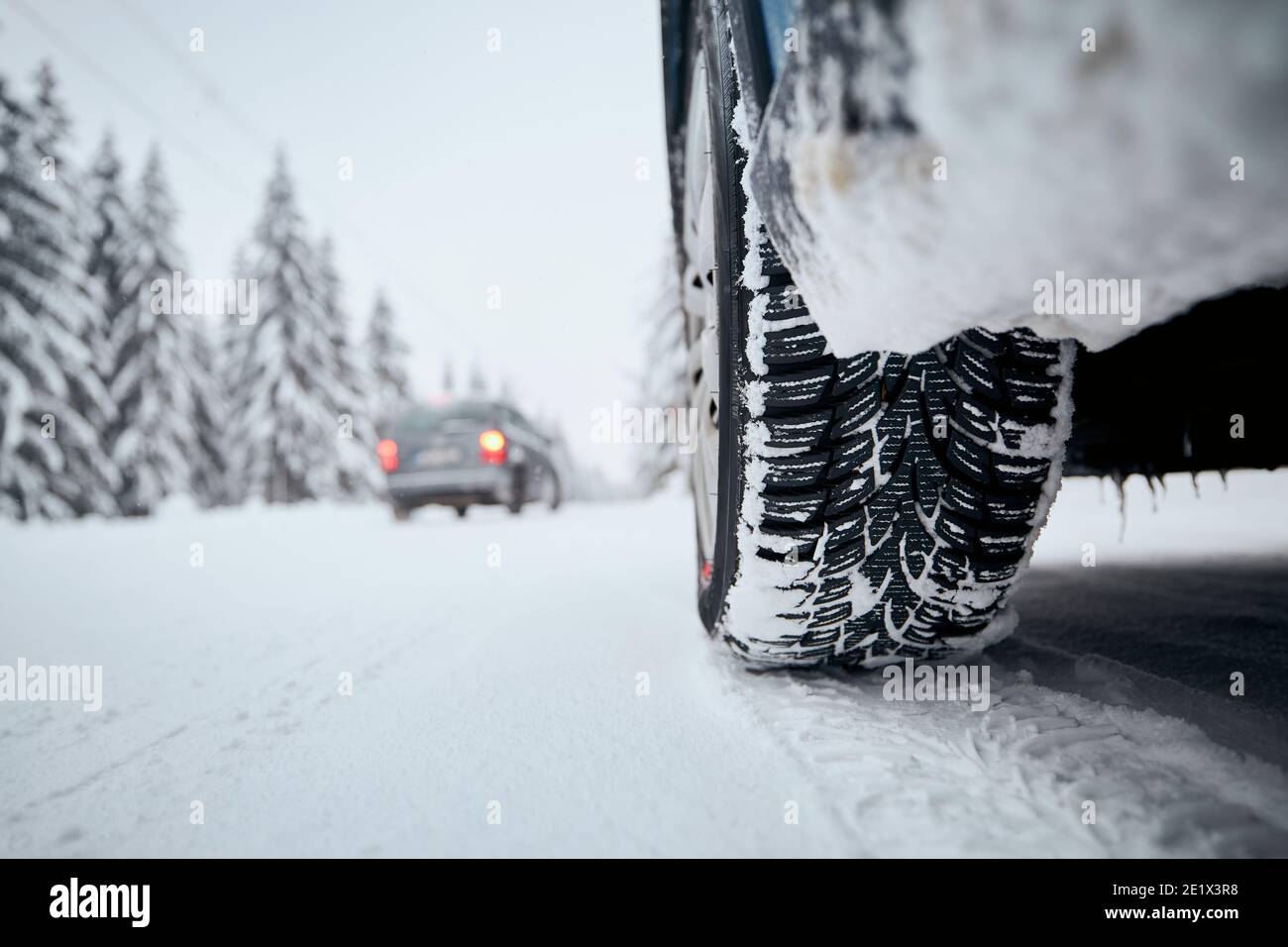 Vista ravvicinata dello pneumatico della vettura su strade innevate e ghiacciate. Temi sicurezza e guida in inverno. Foto Stock