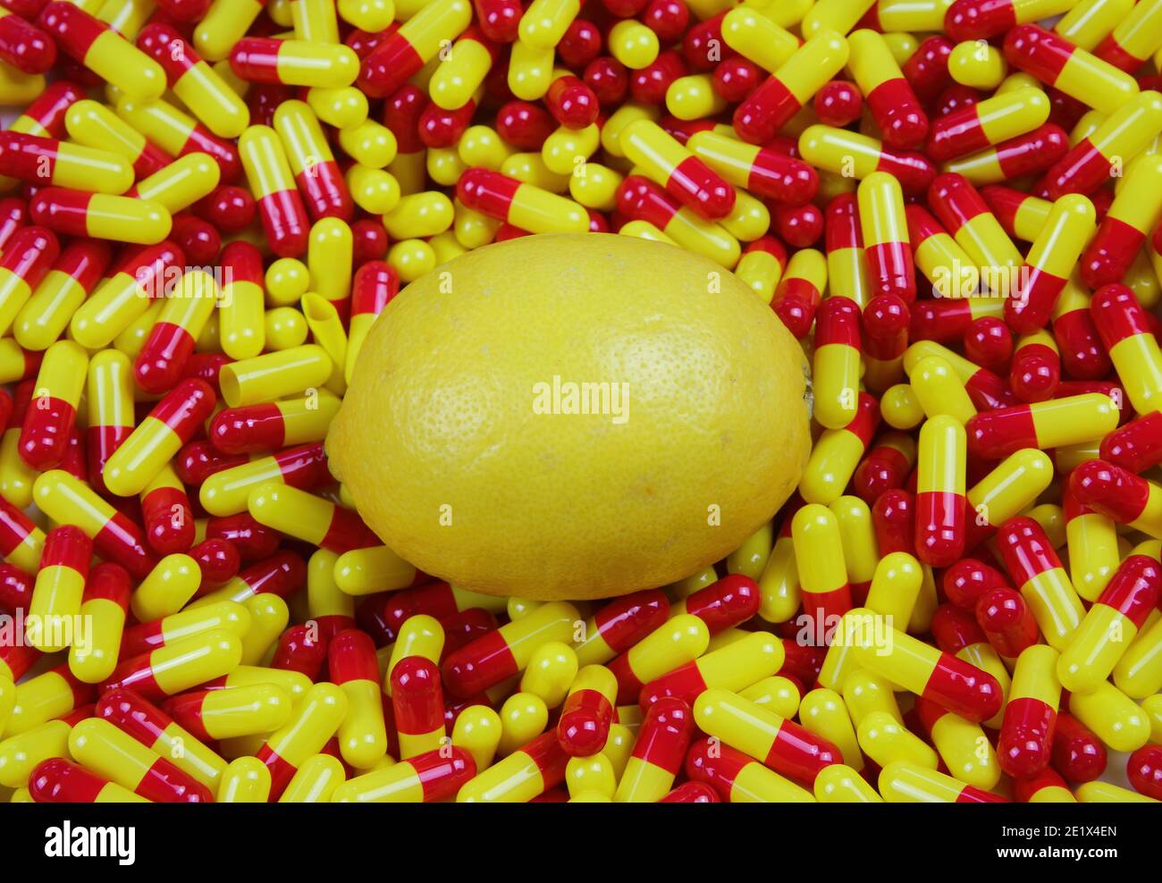 Primo piano di un limone crudo maturo su colorful medico Capsule rosse gialle - concetto di supplemento di vitamina C. (focus sul centro) Foto Stock