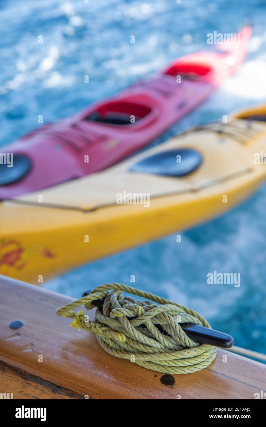 Kayak colorati legati insieme trainati da una nave e alcuni funi a vela in primo piano Foto Stock