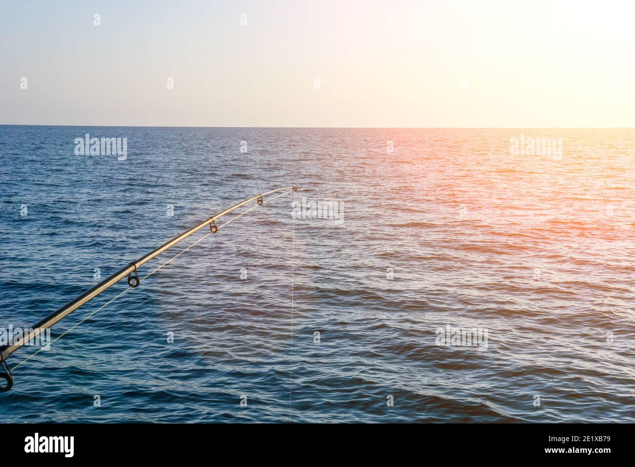 Canna da pesca. Attrezzatura da pesca. Pesca che gira bobina. Illuminazione soffusa. Copyspace con messa a fuoco selettiva Foto Stock