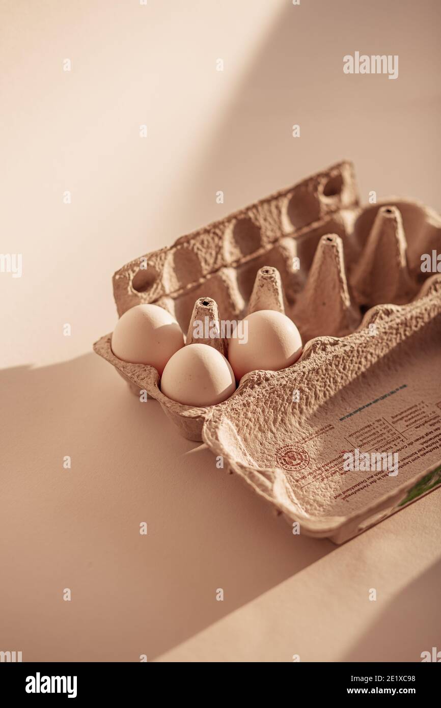 Uova bianche nel cartone delle uova su fondo neutro (natura morta del cibo) Foto Stock