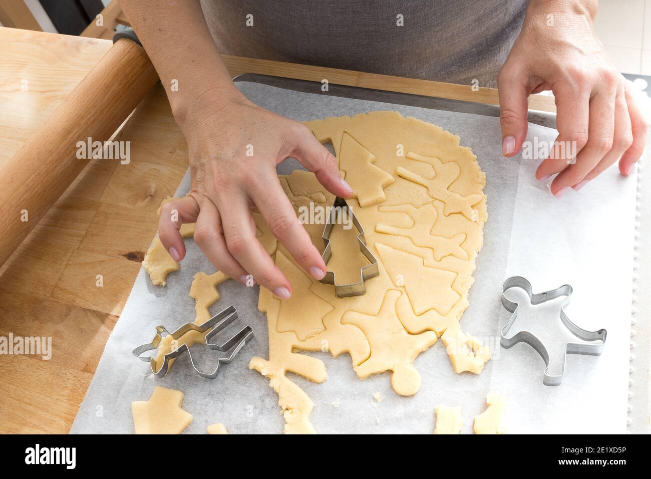 Donna che forma biscotti di forme diverse con stampi metallici da un pezzo di pasta. Foto Stock