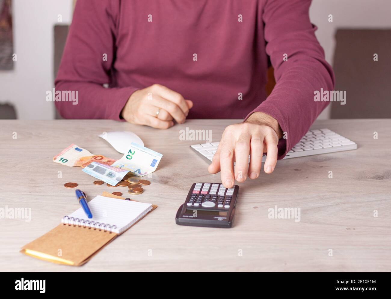 Uomo che fa i calcoli economici al tavolo dell'ufficio con una calcolatrice. Foto Stock