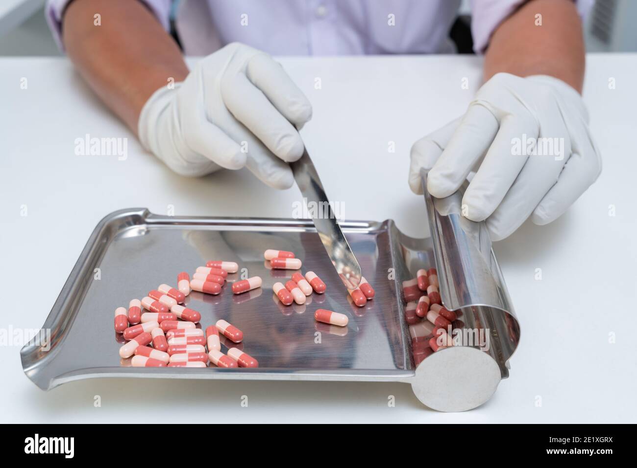 Primo piano mano del farmacista contare il numero di pillole per trattare il paziente nel dosaggio giusto. Medicina e concetto di droga. Foto Stock