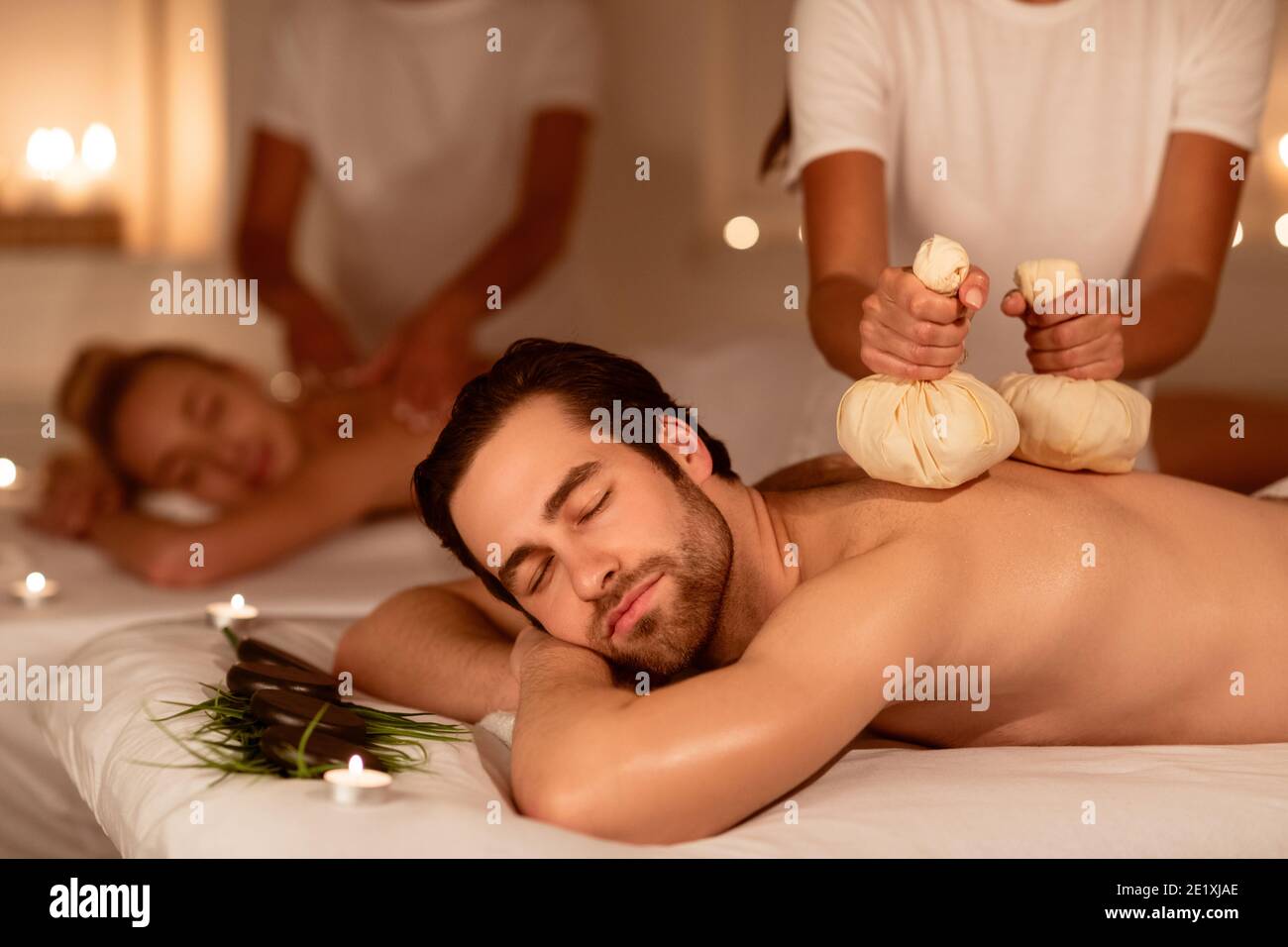 Coppia rilassante durante il massaggio alle erbe con sacche aromatiche all'interno Foto Stock