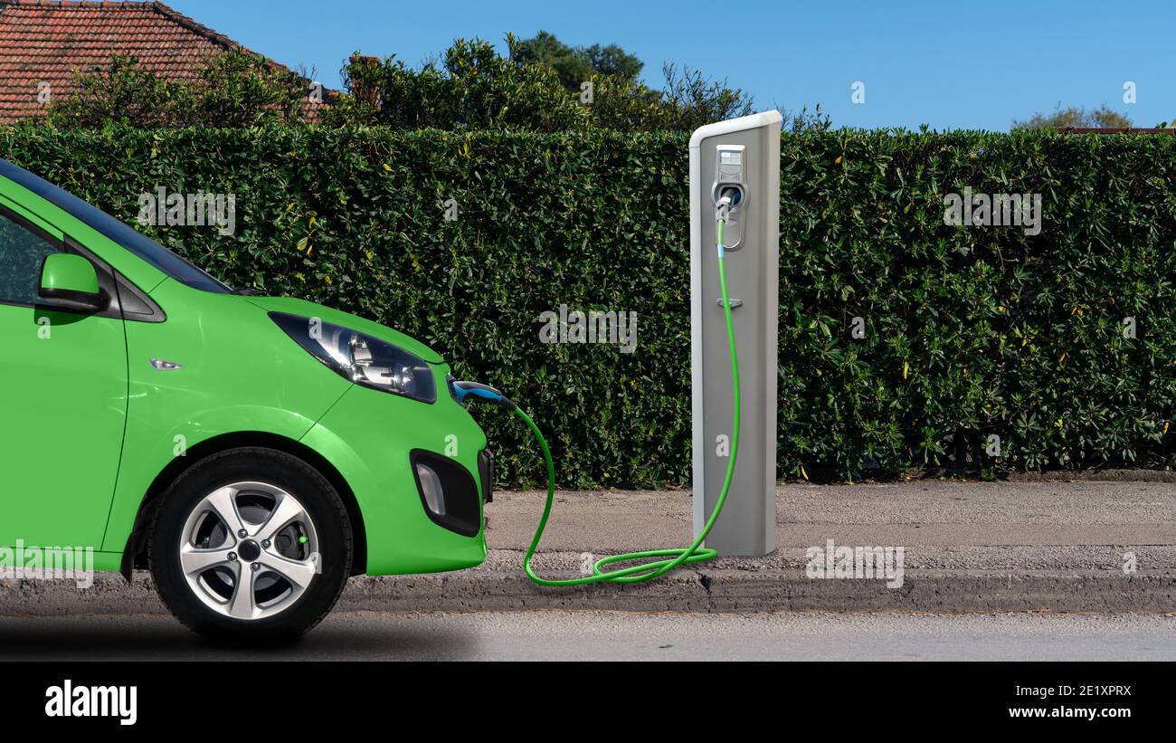 Auto elettrica verde con stazione di ricarica Foto Stock