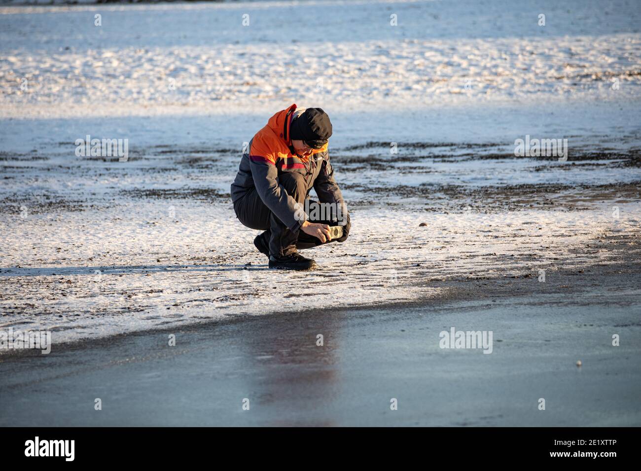 Uomo che fa una foto di ghiaccio sulla spiaggia di Hietaranta a Helsinki, Finlandia Foto Stock