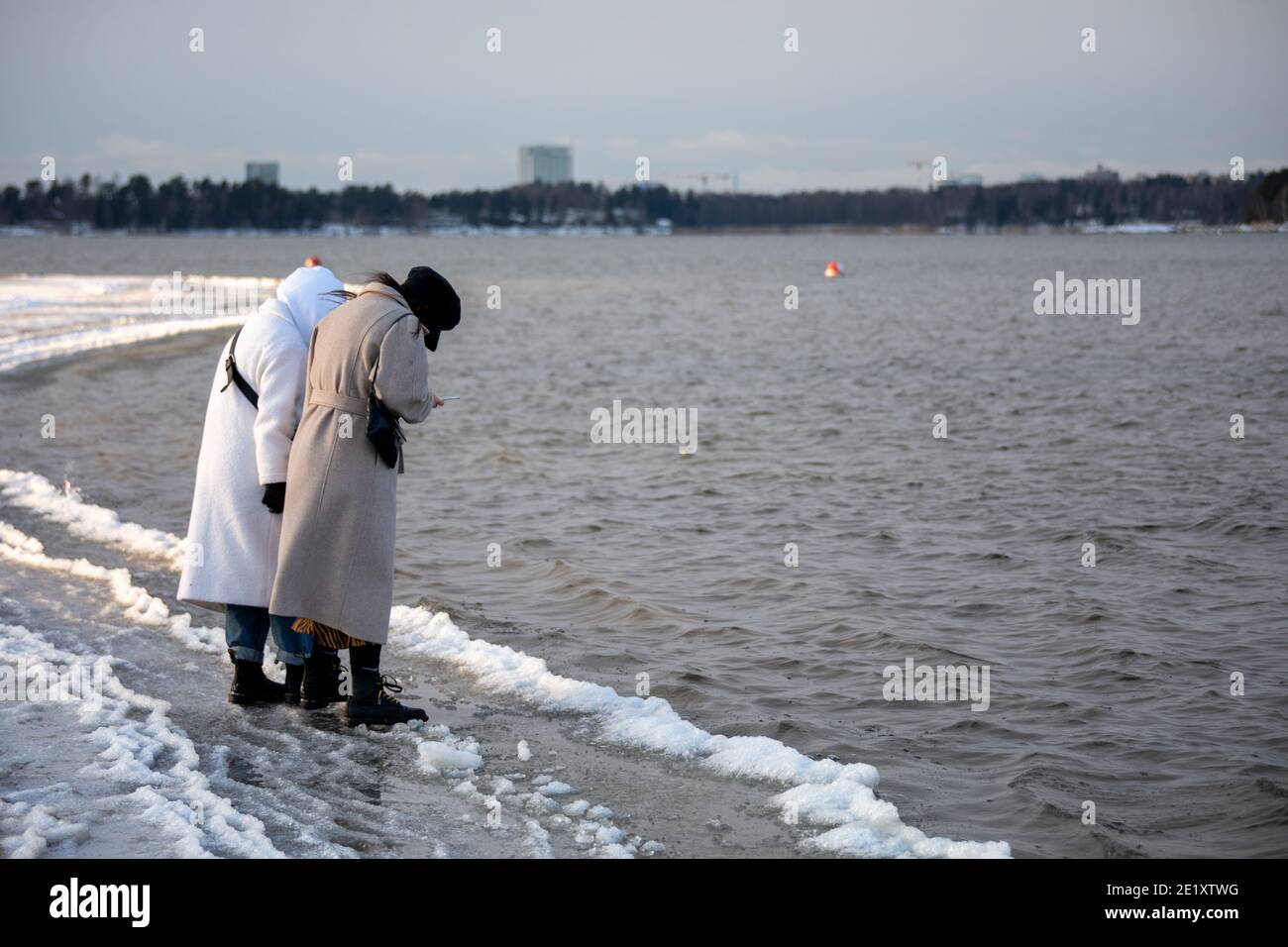Due donne che scattano foto della formazione di ghiaccio alla spiaggia di Hietaranta a Helsinki, Finlandia Foto Stock