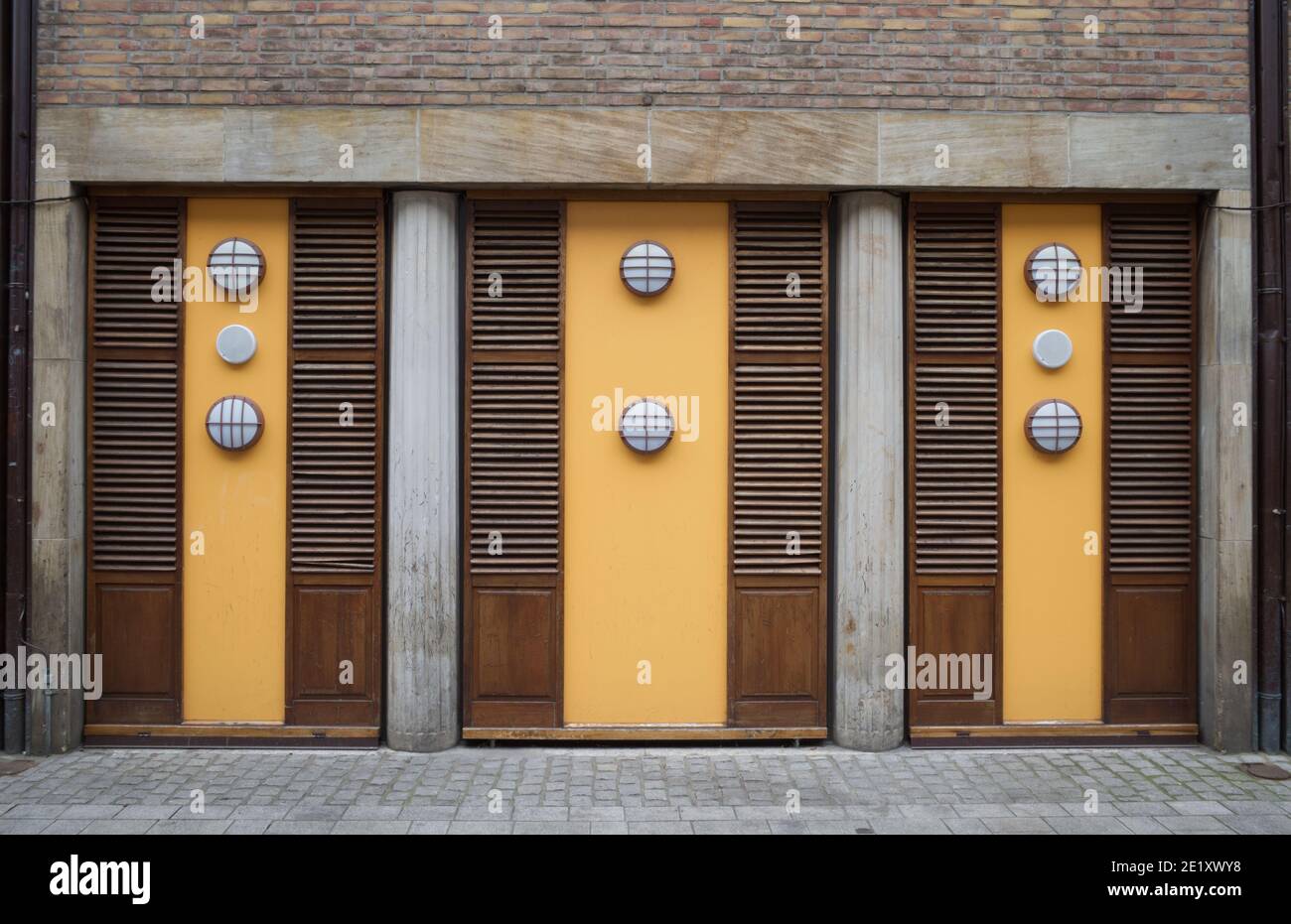 Vista esterna di stile unico con combinazione di legno, pannello giallo, mattoni, pietra di granito e lampada da parete sul marciapiede nella città vecchia. Foto Stock