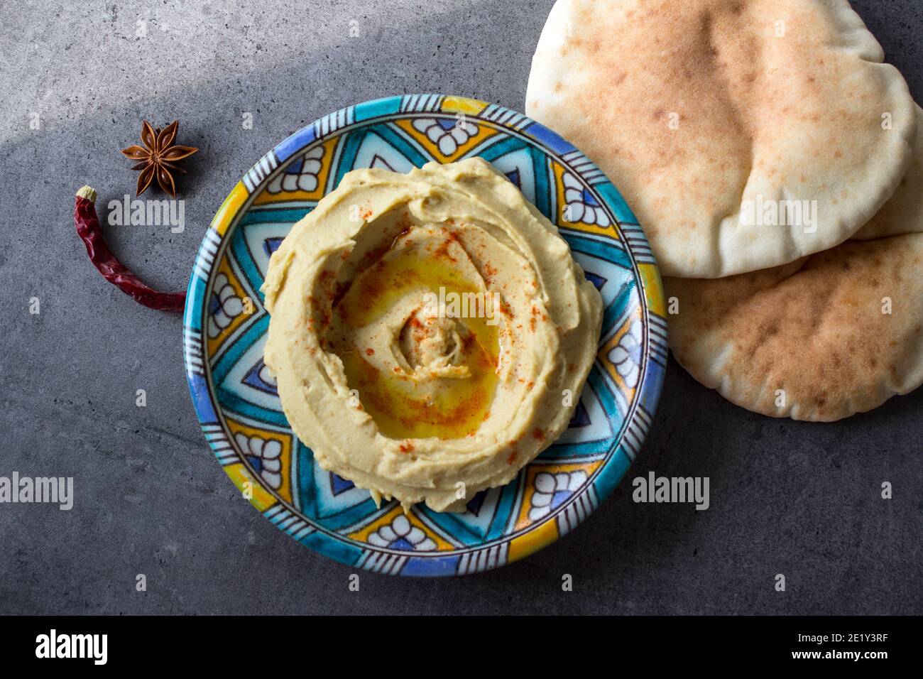 Primo piano foto di un hummus fresco fatto in casa su una colorata piastra in ceramica. Foto pasto bilanciato. Concetto di alimentazione sana. Cibo autentico del Medio Oriente. Foto Stock