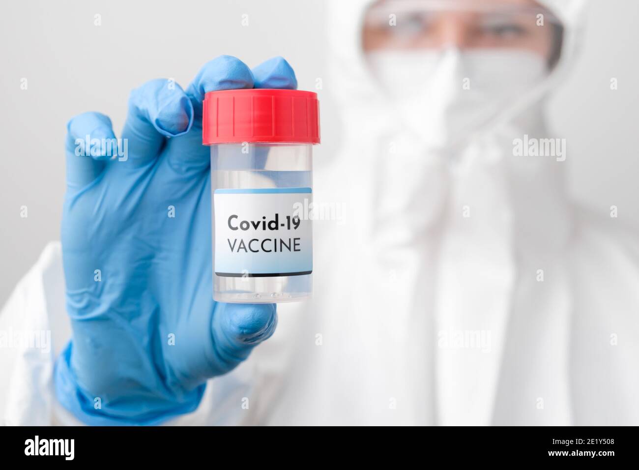 Covid 19 flacone di vaccino in mano medici. Il medico in tuta protettiva, maschera facciale, occhiali di sicurezza e guanti di gomma dimostrano il vaccino contro Foto Stock