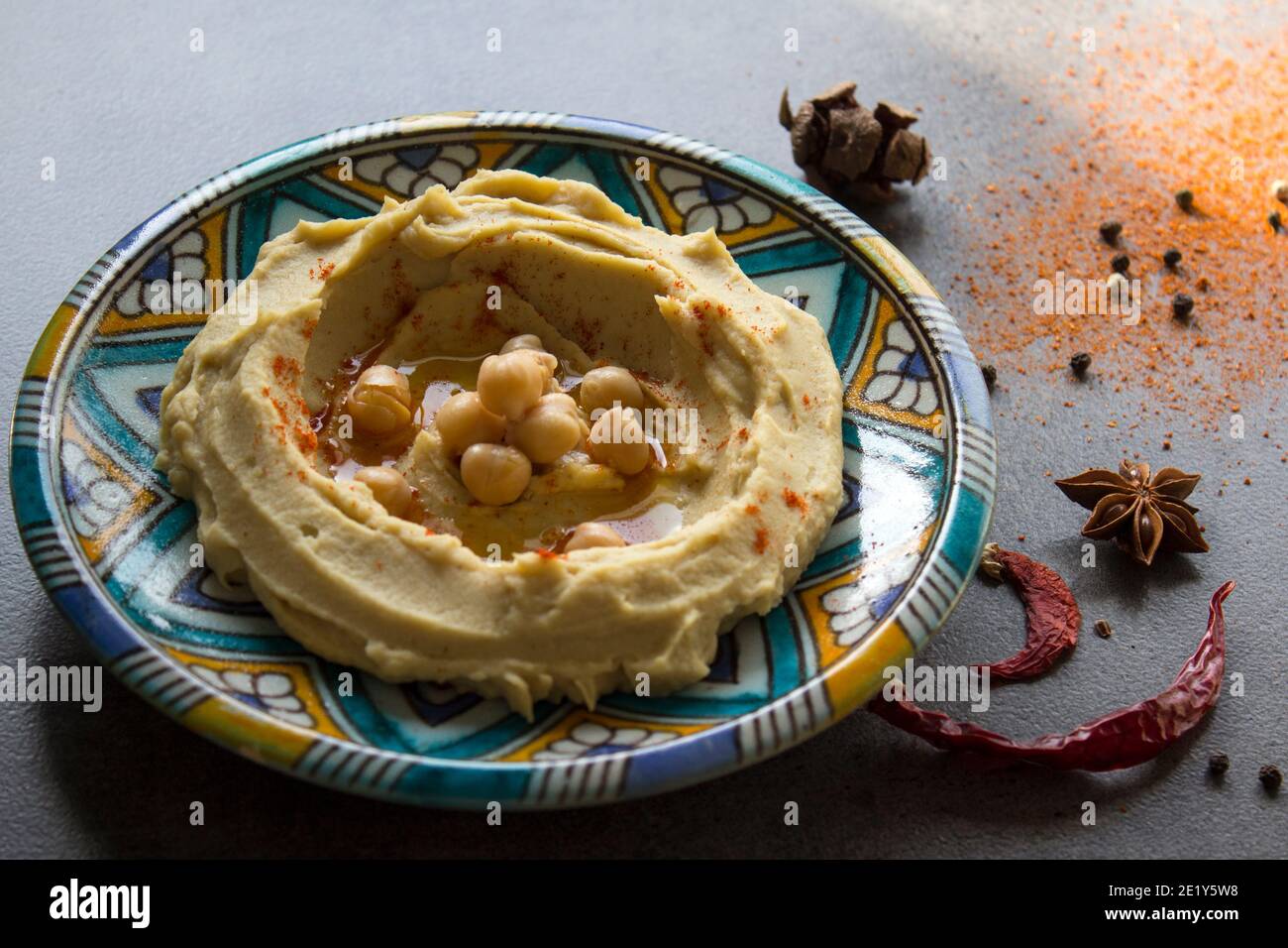 Primo piano foto di un hummus fresco fatto in casa su una colorata piastra in ceramica. Foto pasto bilanciato. Concetto di alimentazione sana. Cibo autentico del Medio Oriente. Foto Stock