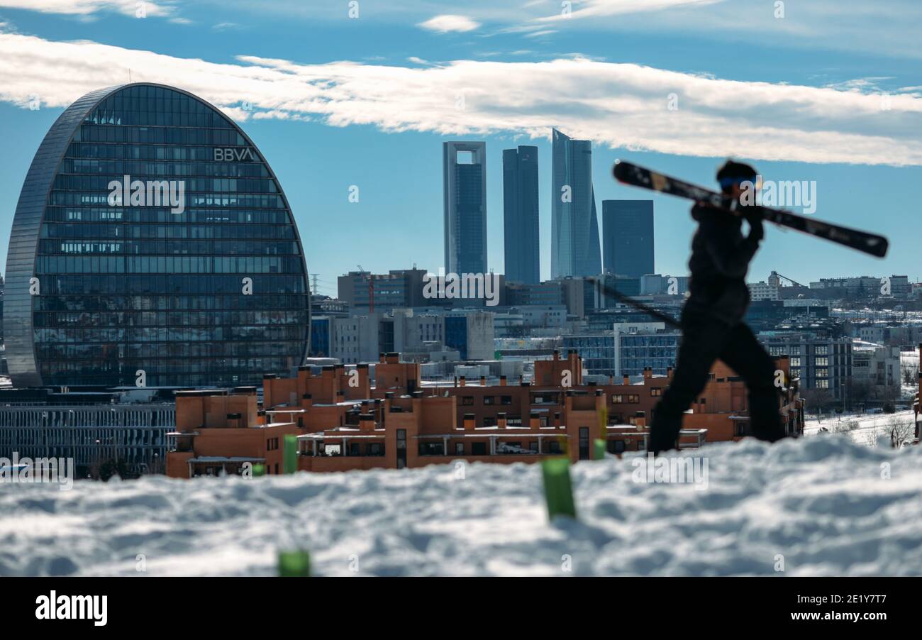 Madrid, Spagna - 10 gennaio 2021 - un uomo in sci che domina i grattacieli del quartiere finanziario di Madrid a seguito di una pesante nevicata a Madrid Foto Stock