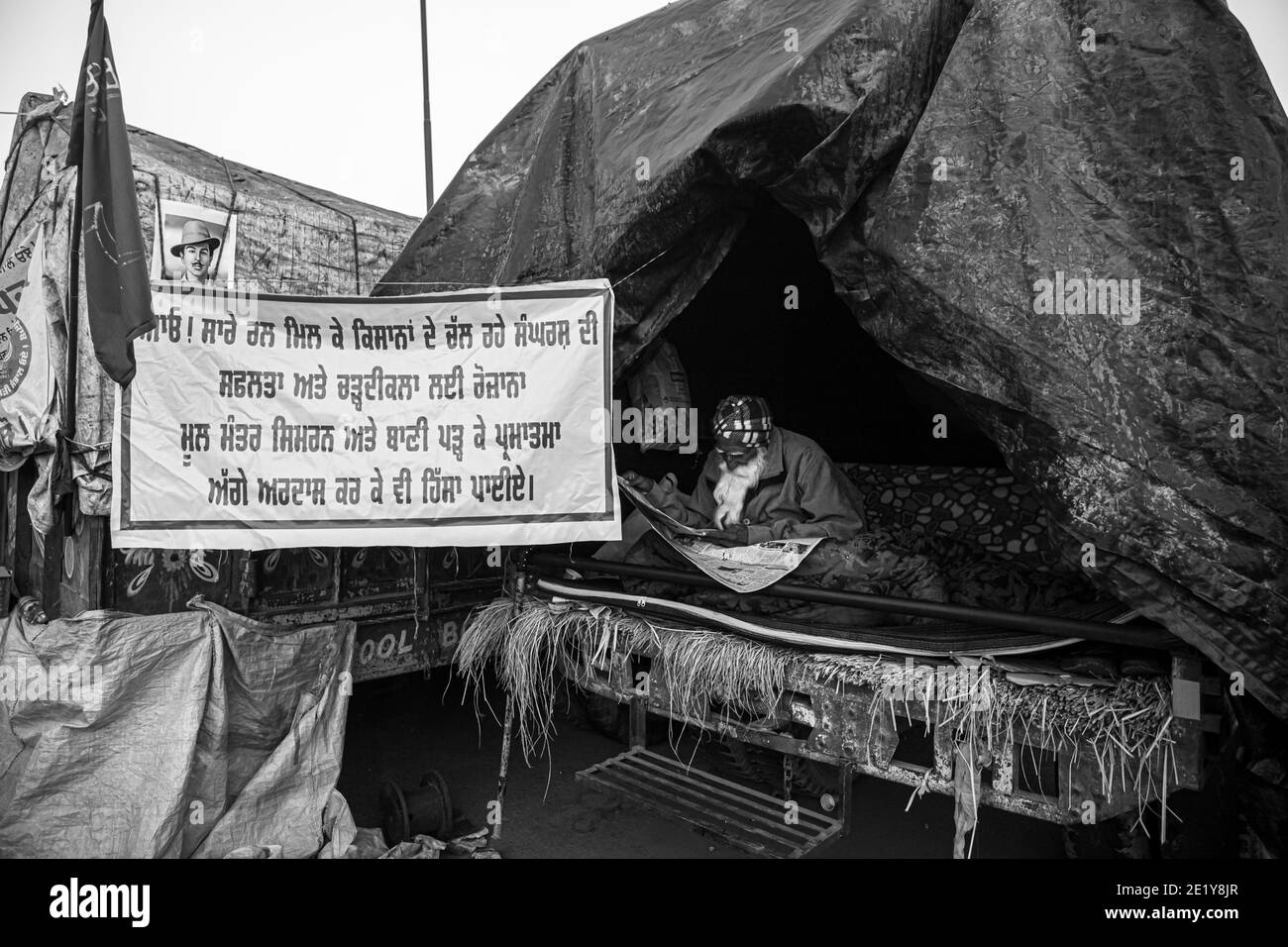 UN RITRATTO DI UN PROTESTANTE CONTADINO CHE LEGGE NOTIZIE AL CONFINE DI DELHI , PROTESTANO CONTRO LA NUOVA LEGGE AGRICOLA APPROVATA DAL GOVERNO INDIANO. Foto Stock