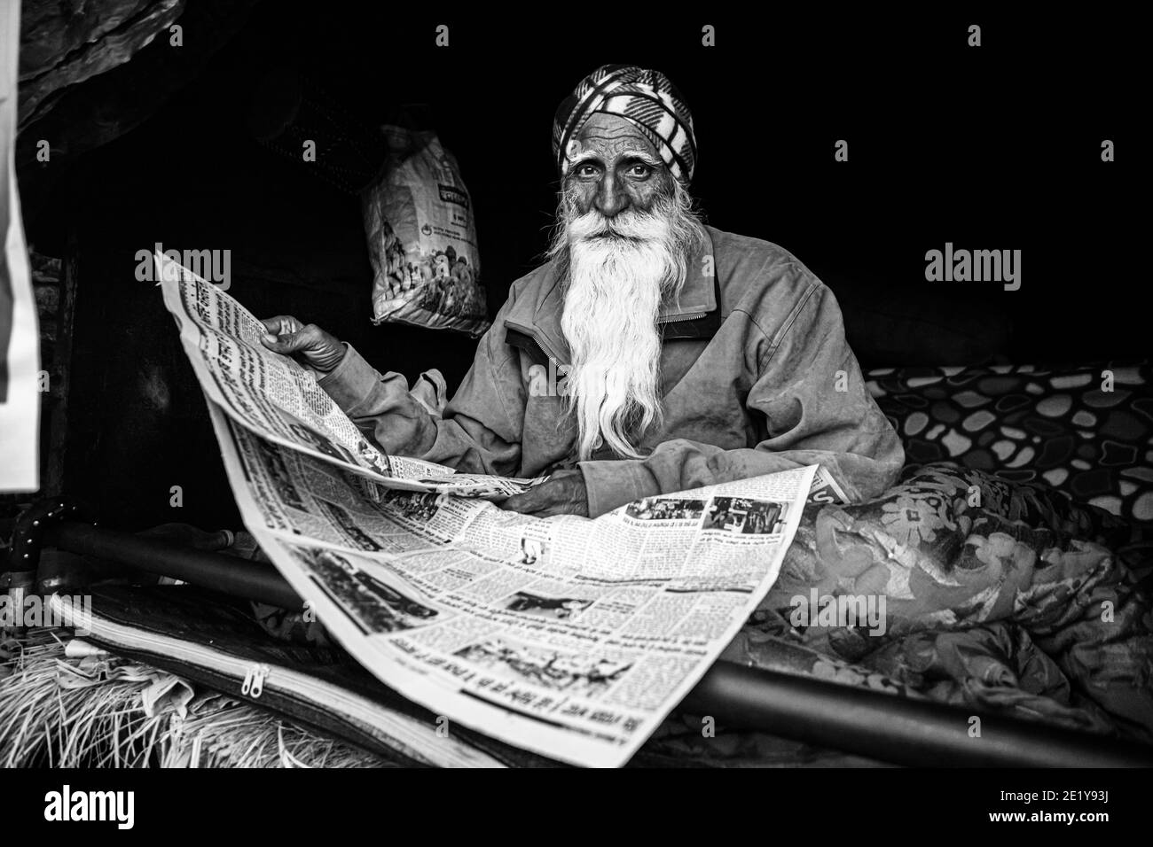 UN RITRATTO DI UN PROTESTANTE CONTADINO CHE LEGGE NOTIZIE AL CONFINE DI DELHI , PROTESTANO CONTRO LA NUOVA LEGGE AGRICOLA APPROVATA DAL GOVERNO INDIANO. Foto Stock