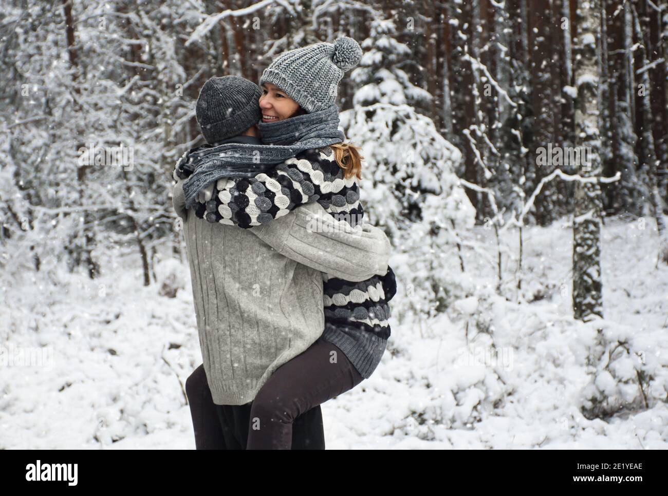 una coppia felice che si agganata in una passeggiata nella foresta innevata Foto Stock