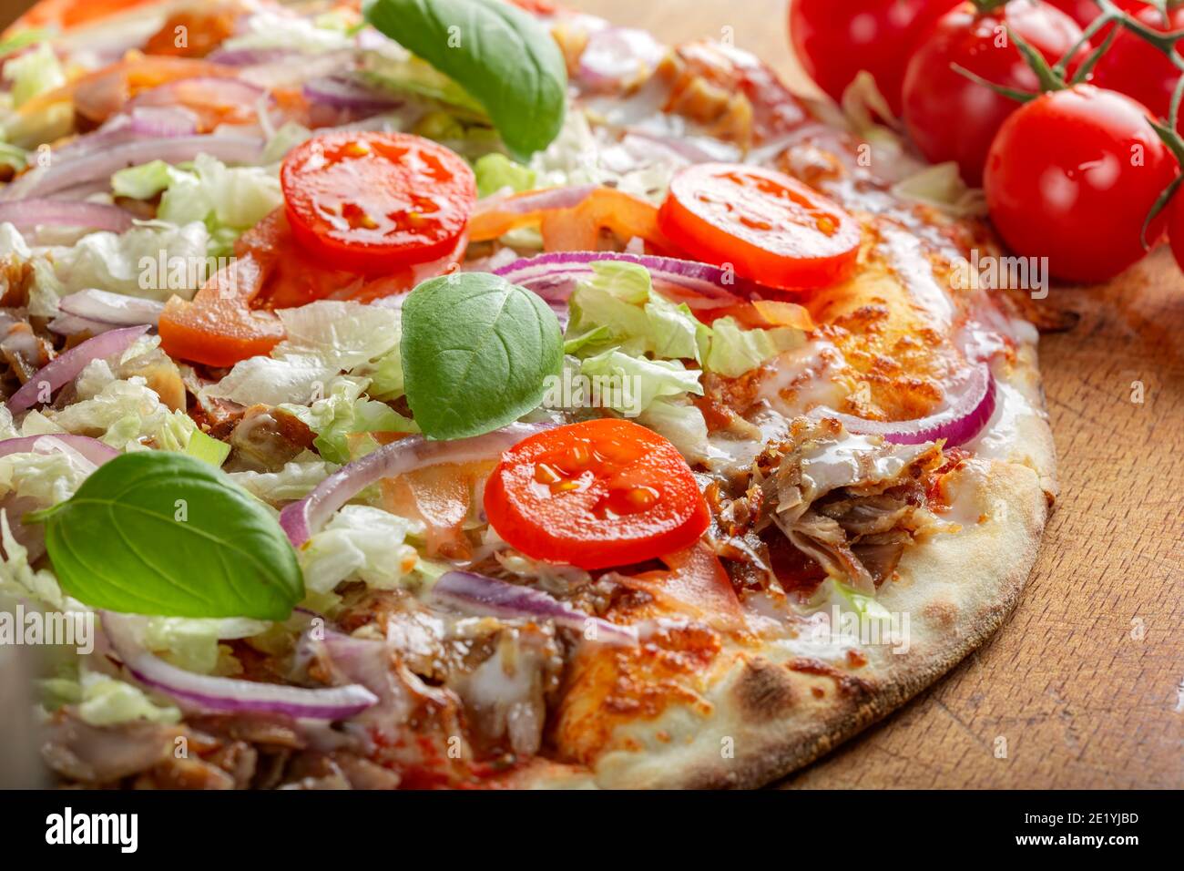 Pizza kebab con fette di pomodoro e foglie di basilico verde Foto Stock