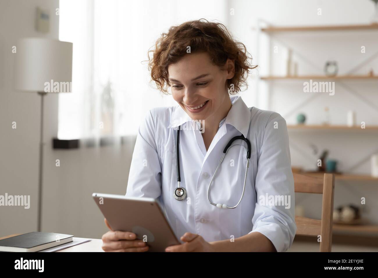 Happy 35s dottore di sesso femminile che usa l'applicazione software su tablet digitale. Foto Stock