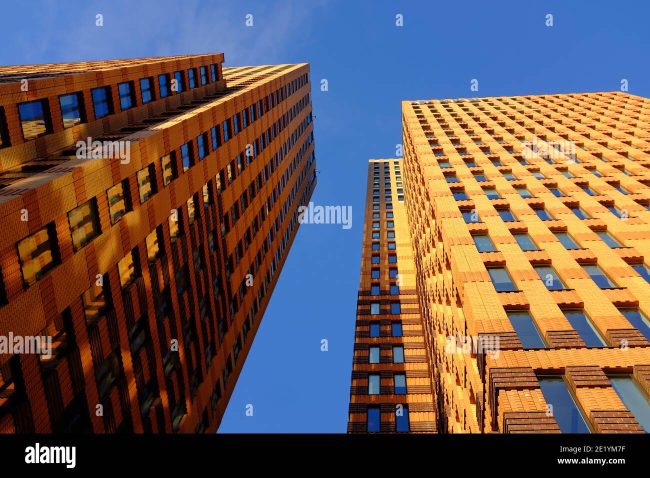 Alti edifici fotografati dal basso sull'Amsterdam Zuidas in una giornata di sole con un cielo blu e leggermente nuvoloso. Foto Stock