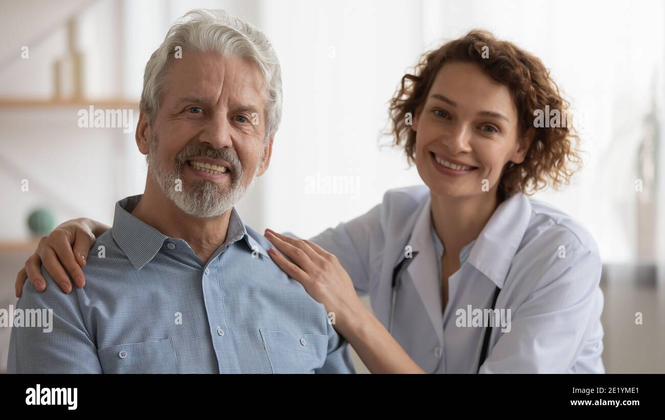 Ritratto di un'infermiera sorridente che abbraccia le spalle del vecchio. Foto Stock