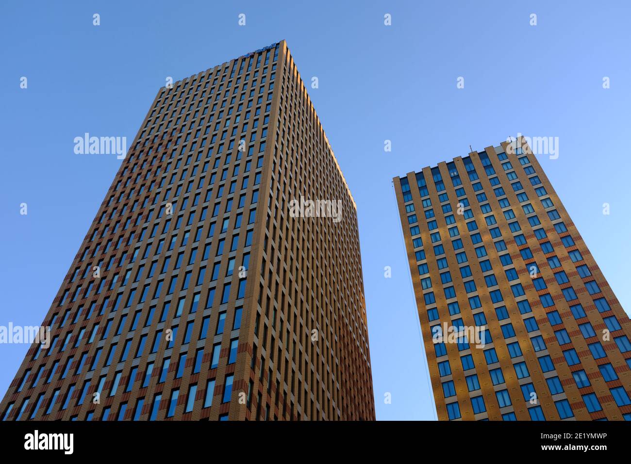 Alti edifici fotografati dal basso sull'Amsterdam Zuidas in una giornata di sole con un cielo blu e leggermente nuvoloso. Foto Stock