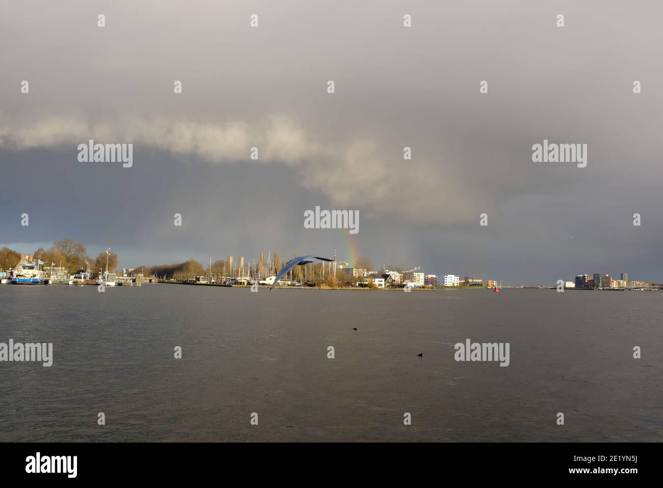 Un bel po' arcobaleno sopra il Noord di Amsterdam come visto da Il fiume IJ Foto Stock