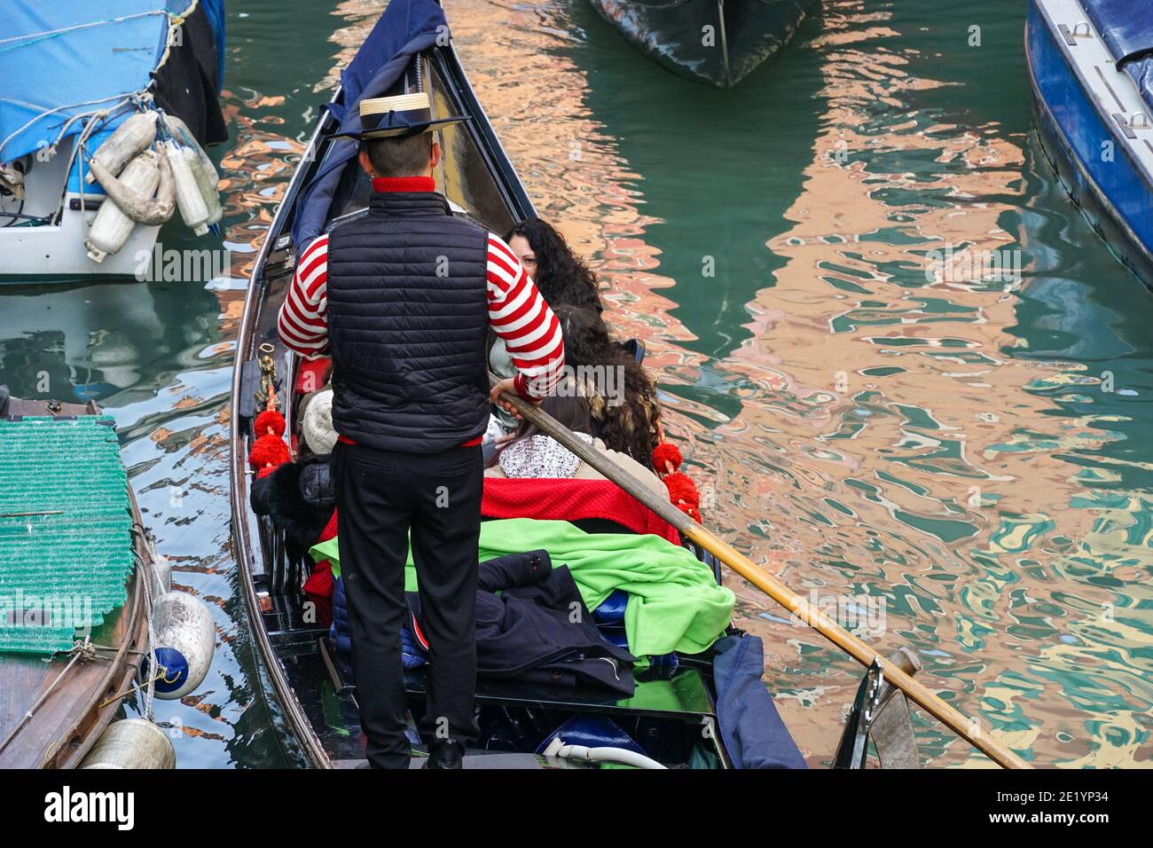 Gondoliere sulla tradizionale gondola veneziana con turisti sul canale a Venezia, Italia Foto Stock