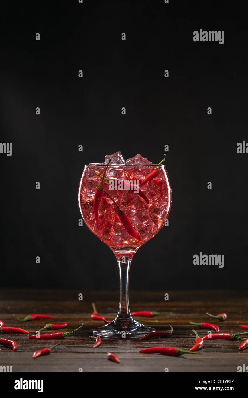 Cocktail rosso in un bicchiere con ghiaccio e peperoncini. Concetto di San Valentino Foto Stock