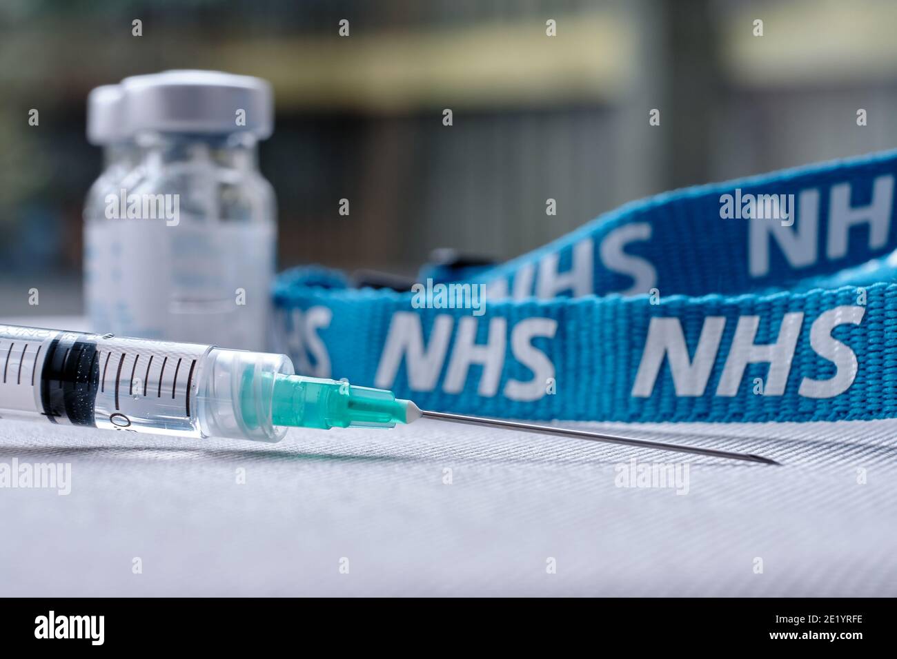 Stafford, Regno Unito - Gennaio 10 2021: Concetto di vaccino NHS. Siringa, flaconcini per iniezione e cordino NHS. Messa a fuoco selettiva. Foto Stock