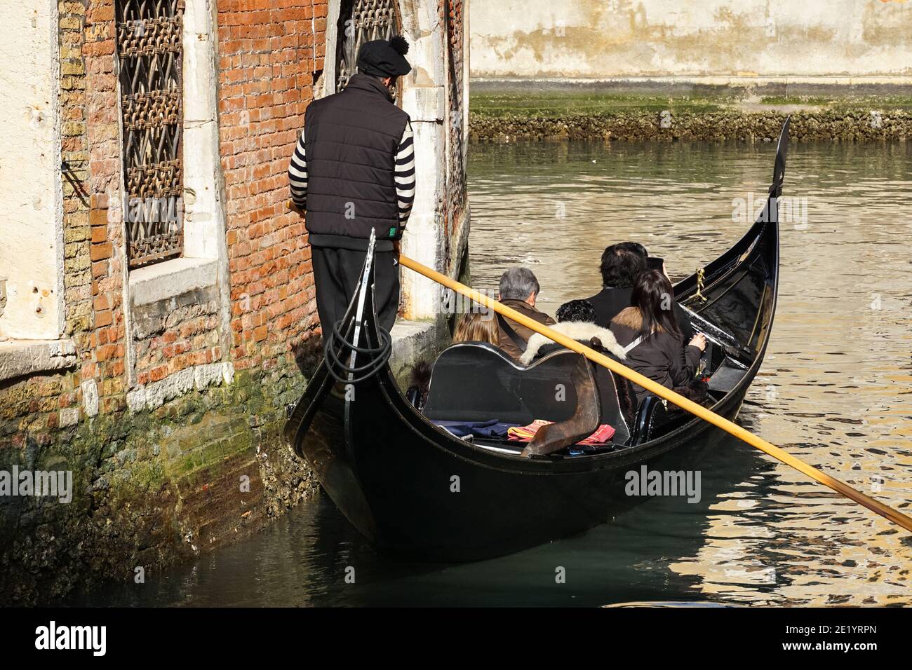 Gondoliere sulla tradizionale gondola veneziana con turisti sul canale a Venezia, Italia Foto Stock