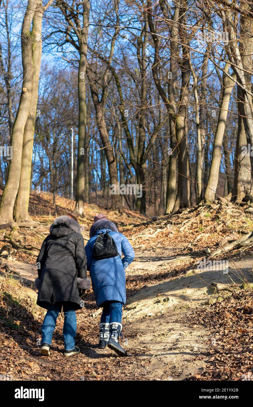 Due ragazze vanno in salita. Donna trekking attraverso boschi verdi vegetazione, in salita. Turismo e concetto di viaggio Foto Stock